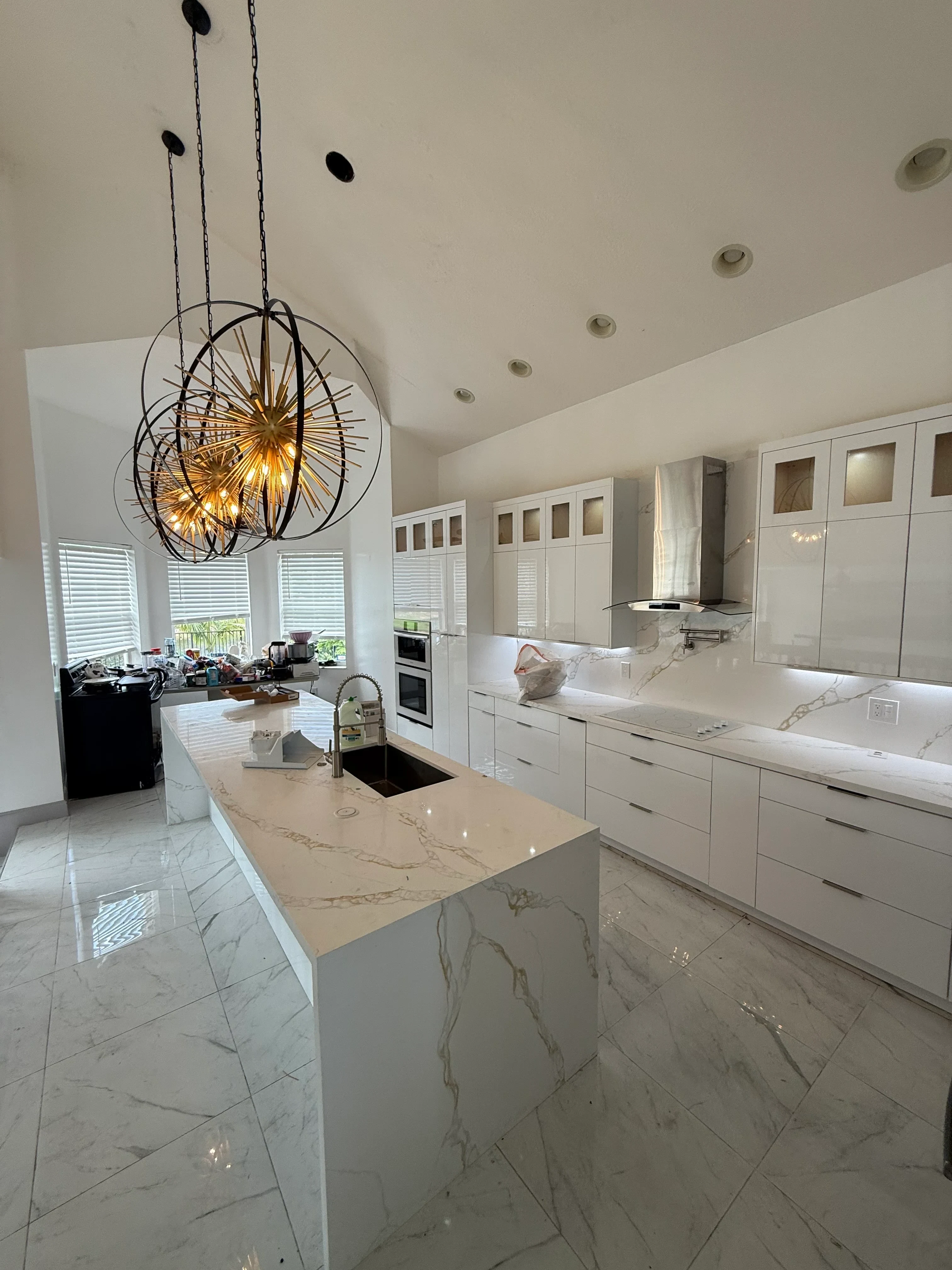 White custom kitchen cabinets with glass doors, marble countertops, and recessed lighting