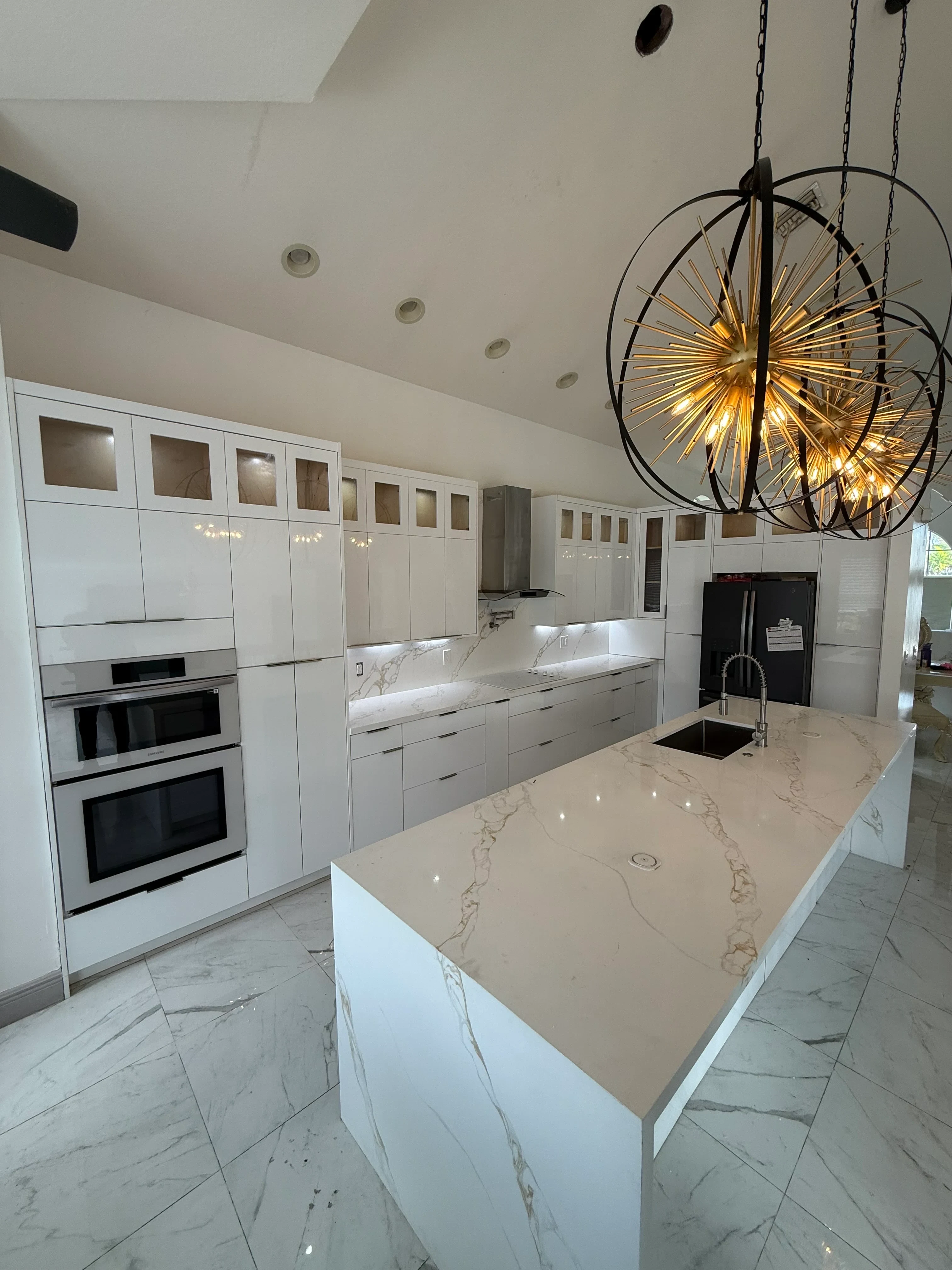 White kitchen cabinets with marble countertops, recessed lighting, and black appliances
