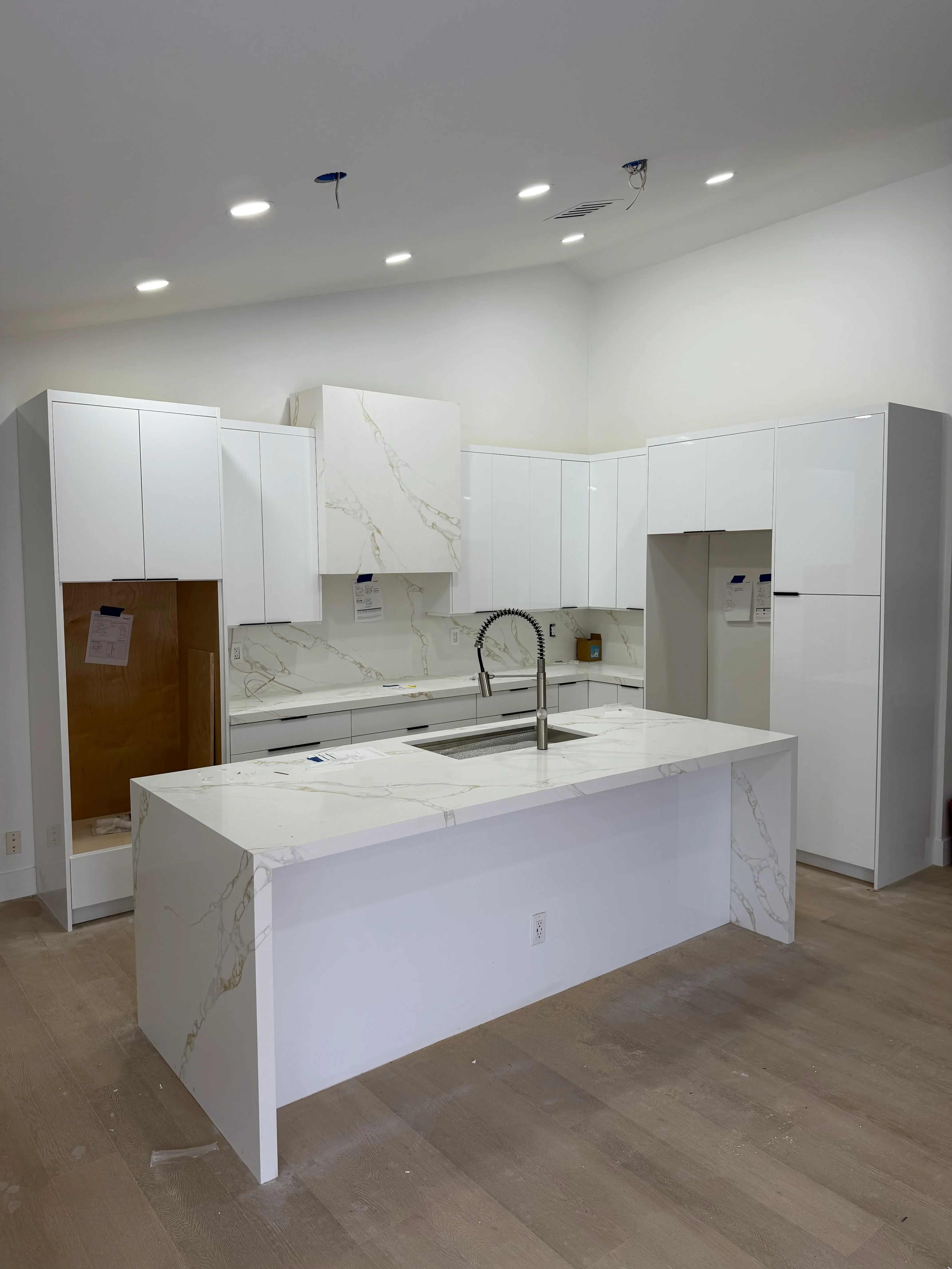 White custom kitchen cabinets with marble quartz countertops and stainless steel hardware